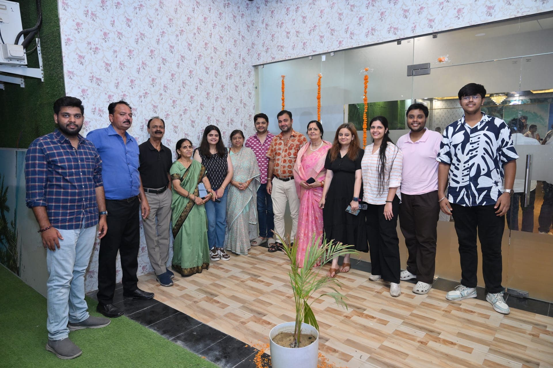 An extended family lined up with marigold garlands at the door