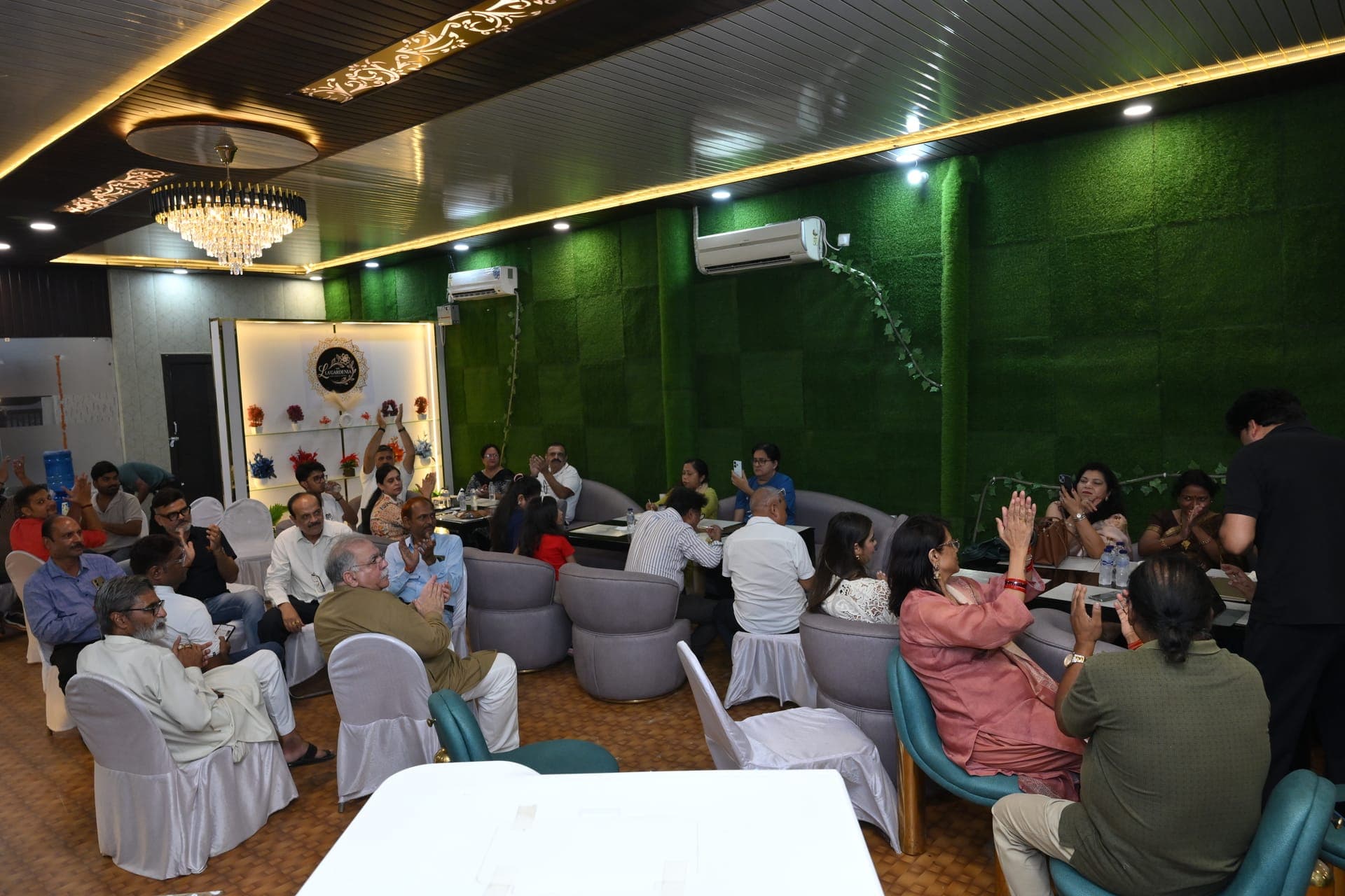 A room full of guests applauding during an evening event